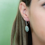 The picture shows a model wearing a 925 sand dollar earring with cubic zirconia.