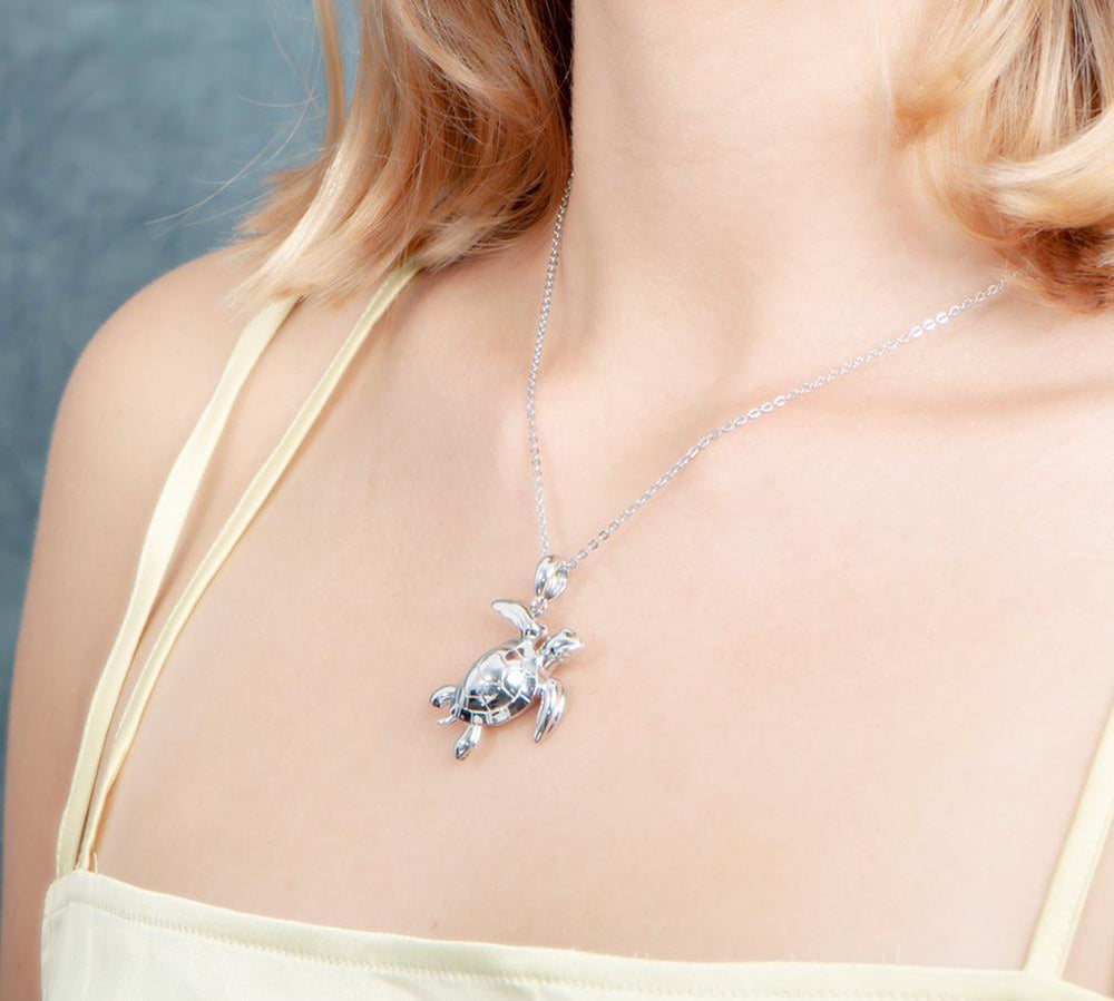 The picture shows a model wearing a 925 sterling silver sea turtle pendant.