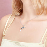 The picture shows a model wearing a 925 sterling silver dolphin pendant with cubic zirconia.
