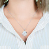 The picture shows a model wearing a 925 sterling silver, white gold plated, pavé barrel jellyfish pendant with topaz.