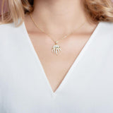 The picture shows a model wearing a 925 sterling silver, yellow gold plated, pavé barrel jellyfish pendant with topaz.