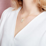 The picture shows a model wearing a 925 sterling silver, yellow gold plated, pavé barrel jellyfish pendant with topaz.
