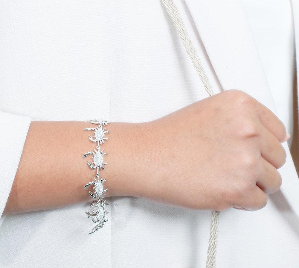 The picture shows a model wearing a 925 sterling silver white gold plated blue crab bracelet with topaz.