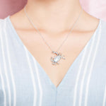 The picture shows a model wearing a 925 sterling silver, white gold plated, pavé blue crab pendant with cubic zirconia.