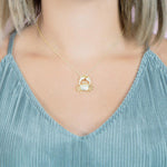 The picture shows a model wearing a 925 sterling silver, yellow gold plated, pavé crab pendant with topaz.