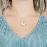 The picture shows a model wearing a 925 sterling silver, yellow gold plated, pavé crab pendant with topaz.