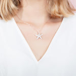 The picture shows a model wearing a 925 sterling silver, yellow gold plated, cushion sea star pendant with topaz.