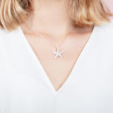 The picture shows a model wearing a 925 sterling silver, yellow gold plated, cushion sea star pendant with topaz.