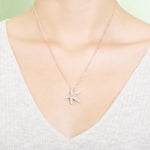 The picture shows a model wearing a 925 sterling silver, rose gold plated, dancing starfish pendant with topaz.