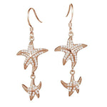 The picture shows a pair of 14K yellow gold pavé diamond starfish hook earrings.
