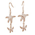 The picture shows a pair of 14K yellow gold pavé diamond starfish hook earrings.