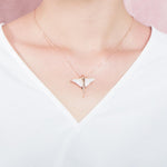The picture shows a model wearing a 925 sterling silver, rose gold plated, pavé eagle ray pendant with cubic zirconia.