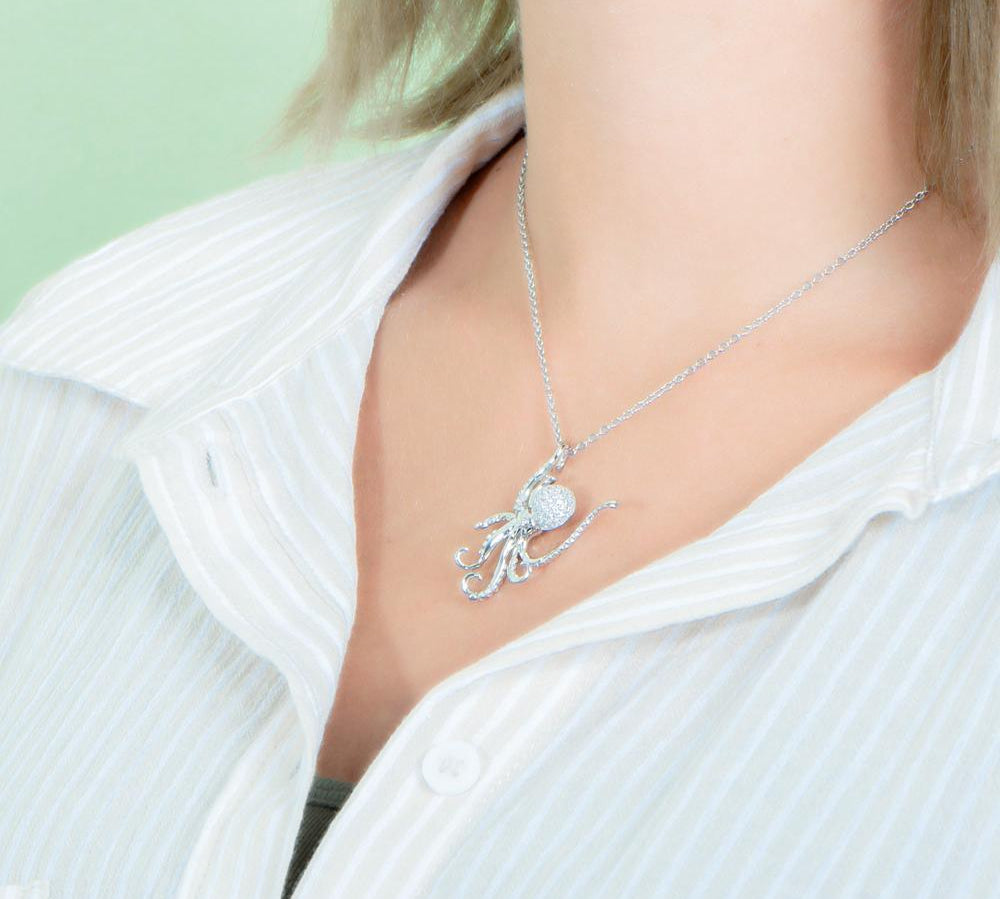 The picture shows a model wearing a 925 sterling silver, white gold vermeil, pavé octopus pendant with topaz.