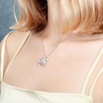 The photo shows a model wearing a white gold pavé hibiscus adorned sea turtle pendant.