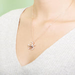 The photo shows a model wearing a rose gold pavé hibiscus adorned sea turtle pendant.