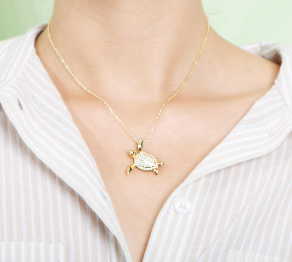 The picture shows a model wearing a 925 sterling silver, yellow gold vermeil, sea turtle pendant with topaz.