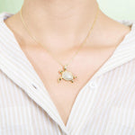 The picture shows a model wearing a 925 sterling silver, yellow gold vermeil, sea turtle pendant with topaz.