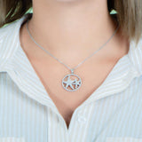 The picture shows a model wearing a 925 sterling silver, white gold vermeil, double starfish circle pendant with topaz.
