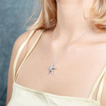 The picture shows a model wearing a 925 sterling silver, white gold vermeil, starfish pendant with topaz.