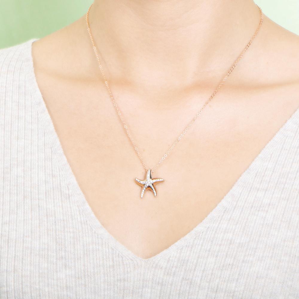 The picture shows a model wearing a 925 sterling silver, rose gold vermeil, starfish pendant with topaz.