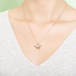 The picture shows a model wearing a 925 sterling silver, rose gold vermeil, starfish pendant with topaz.