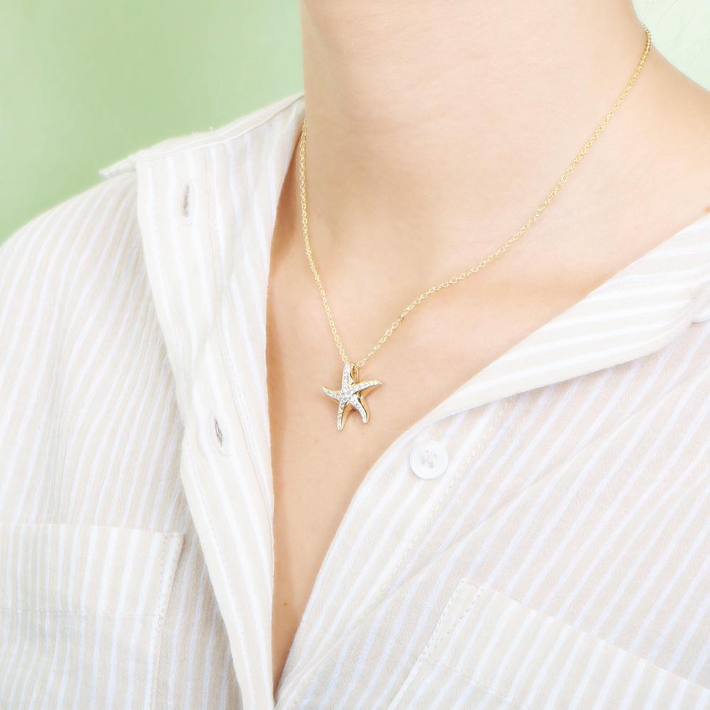 The picture shows a model wearing a 925 sterling silver, yellow gold vermeil, starfish pendant with topaz.