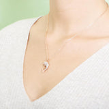 The picture shows a model wearing a 925 sterling silver, rose gold-vermeil, dolphin pendant with cubic zirconia.