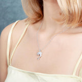 The picture shows a model wearing a 925 sterling silver, white gold-vermeil, dolphin pendant with cubic zirconia.