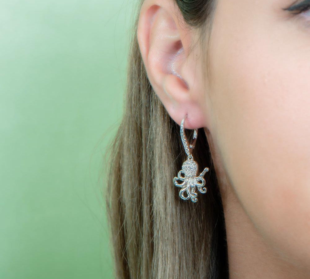The picture shows a model wearing a 925 sterling silver octopus earring with topaz.