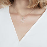 In this photo there is a model with blonde hair and a white shirt, wearing a rose gold double palm tree pendant with topaz gemstones.