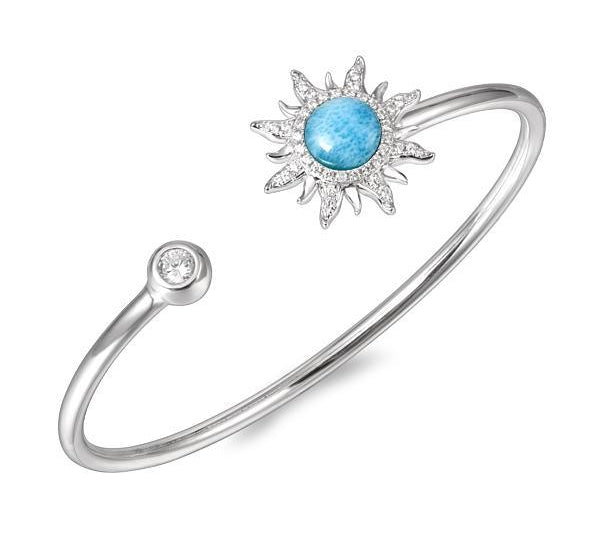 In this photo there is a sterling silver sun bangle with blue larimar, topaz, and aquamarine gemstones.