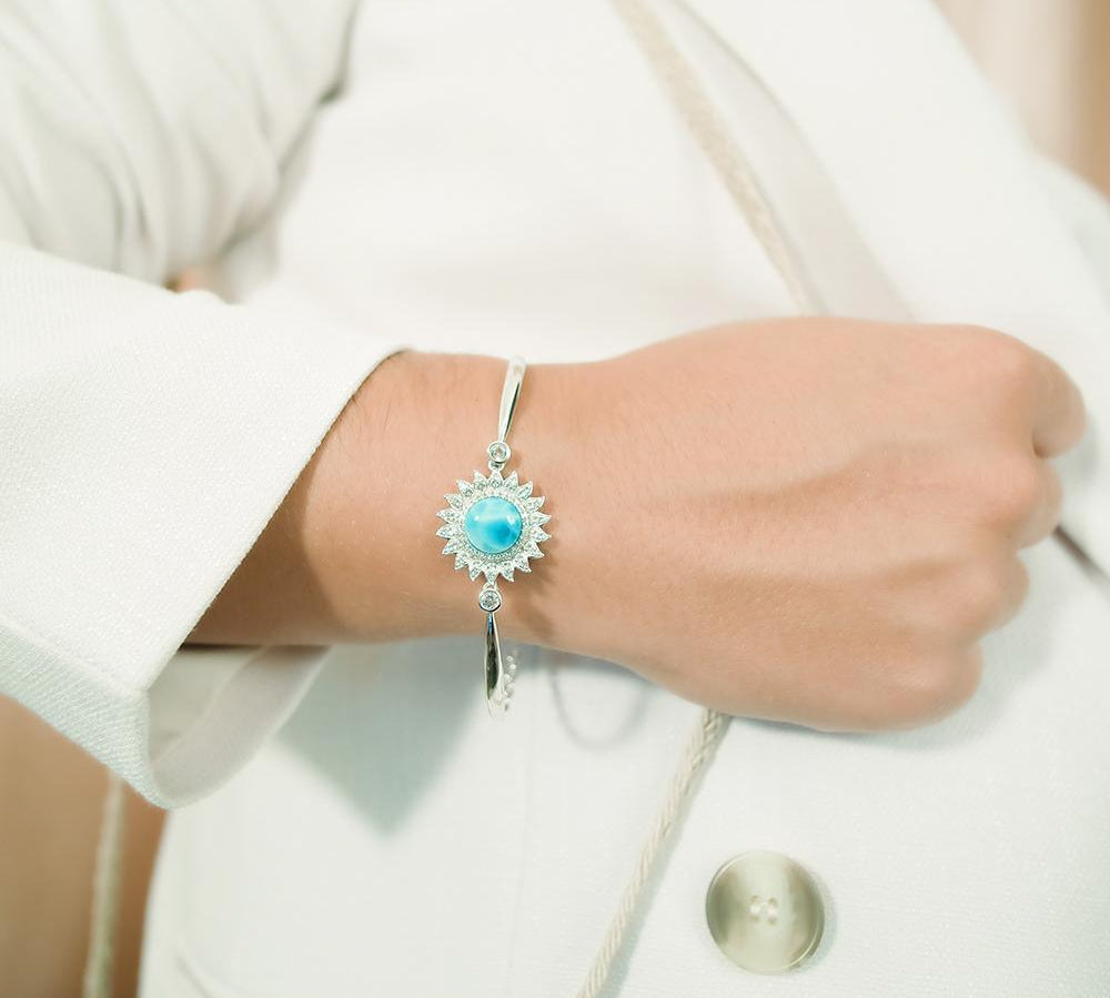 This picture shows a model wearing a 925 sterling silver sunflower bracelet with one blue larimar gemstone and topaz.
