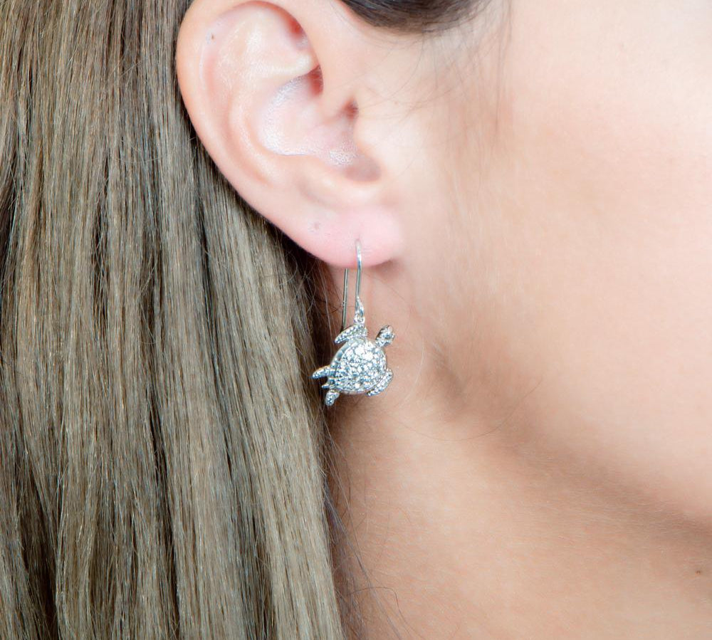 The picture shows a model wearing a 925 sterling silver sea turtle hook earring with topaz.
