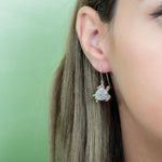 The picture shows a model wearing a 925 sterling silver sea turtle hook earring with topaz.