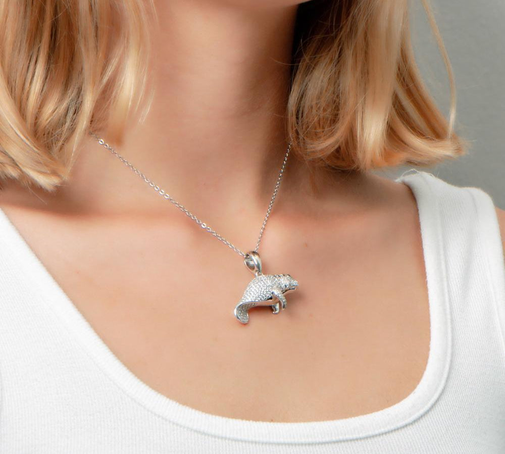 The picture shows a model wearing a 925 sterling silver pavé manatee pendant with cubic zirconia.