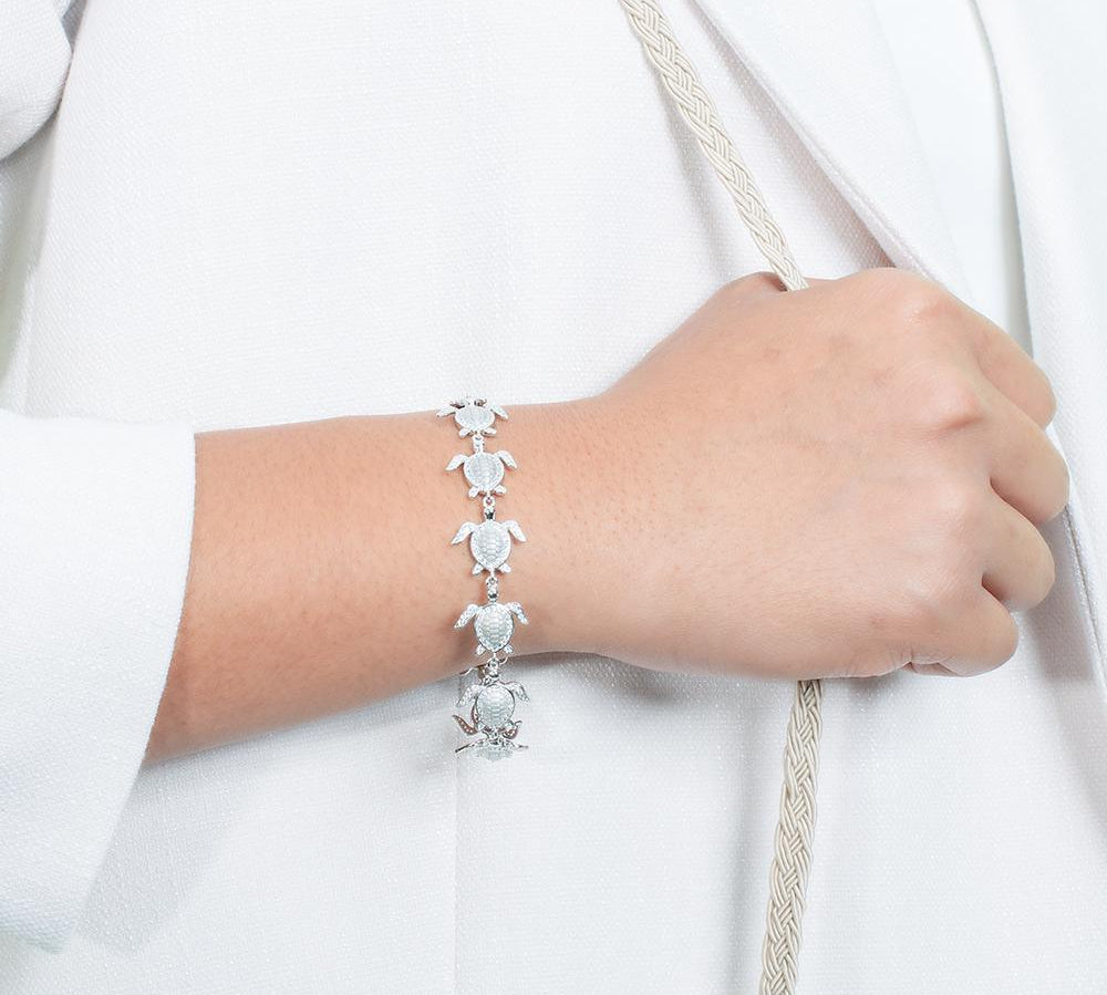 The picture shows a model wearing a 925 sterling silver white gold-plated sea turtle bracelet with cubic zirconia.