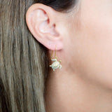 The picture shows a model wearing a 925 sterling silver yellow gold-vermeil sea turtle hook earring with topaz.