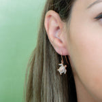 The picture shows a model wearing a 925 sterling silver rose gold-vermeil sea turtle hook earring with topaz.