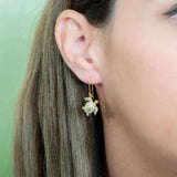 The picture shows a model wearing a 925 sterling silver yellow gold-vermeil sea turtle hook earring with topaz.