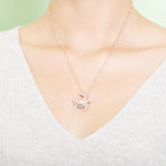 The picture shows a model wearing a 925 sterling silver, rose gold plated, sea turtle pendant with topaz.
