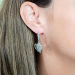 In this photo there is a close-up of a model with brown hair in profile, wearing sterling silver king conch shell earrings with topaz gemstones.
