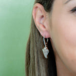 In this photo there is a close-up of a model with brown hair wearing sterling silver king conch shell earrings with topaz gemstones.