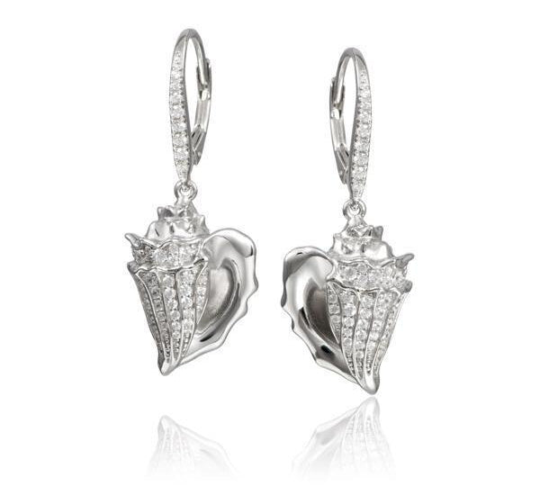 In this photo there is a pair of sterling silver king conch shell earrings with topaz gemstones.