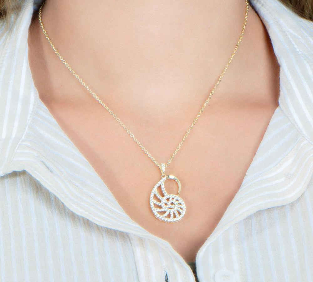 The picture shows a model wearing a 925 sterling silver pavé yellow gold vermeil nautilus shell pendant with topaz.