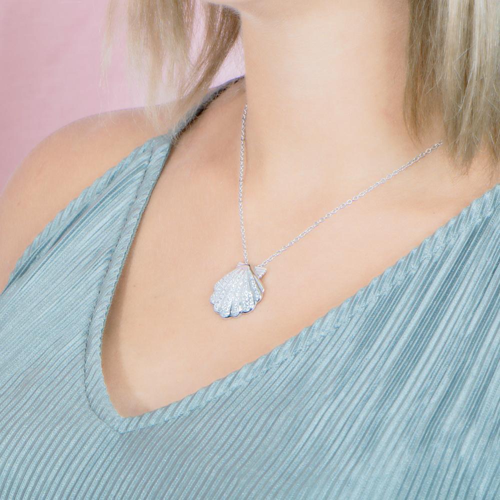 The picture shows a model wearing a 925 sterling silver, white gold-vermeil, pavé oyster shell pendant with topaz.