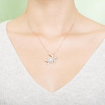 The picture shows a model wearing a 925 sterling silver rose gold vermeil sea turtle pendant with cubic zirconia.