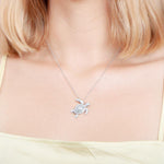 The picture shows a model wearing a 925 sterling silver white gold vermeil sea turtle pendant with cubic zirconia.