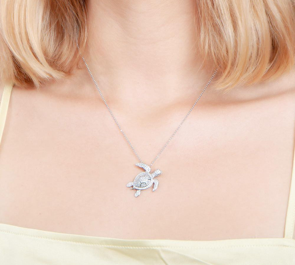 The picture shows a model wearing a 925 sterling silver white gold vermeil sea turtle pendant with cubic zirconia.