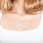 The picture shows a model wearing a 925 sterling silver, white gold vermeil, sailfish pendant with topaz.