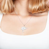 The picture shows a model wearing a 925 sterling silver, white gold vermeil, sailfish pendant with topaz.